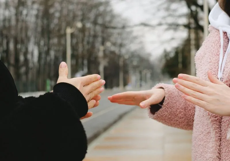 Imagem de duas pessoas se comunicando em linguagem de sinais, com foco em suas mãos