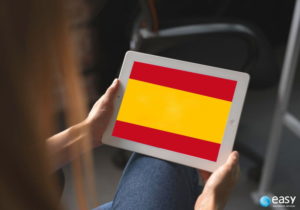 Pessoa segurando tablet com fundo da bandeira da Espanha.