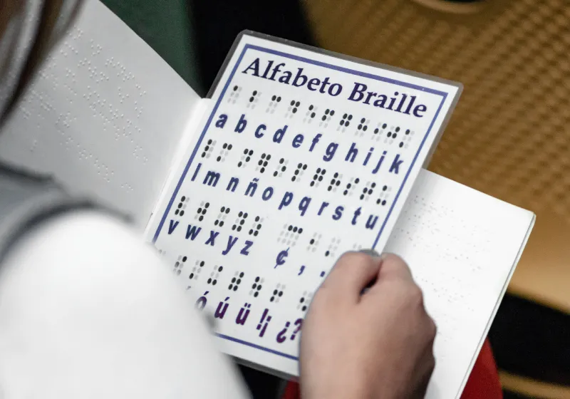 Uma pessoa está com um encarte do Alfabeto em Braille