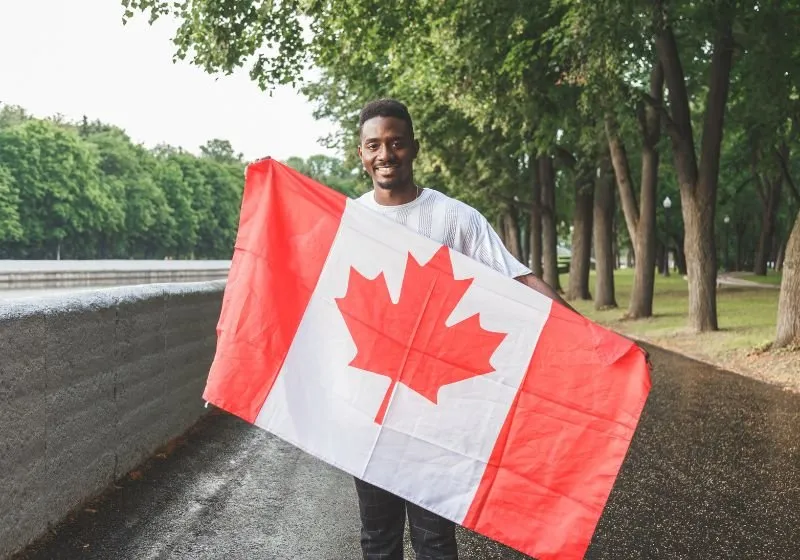 homem negro segurando a bandeira do Canadá ao ar livre 