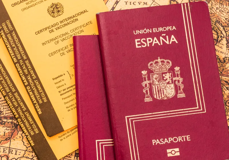 dois passaporte da Espanha com dois certificado internacional de vacina em cima do mapa mundo