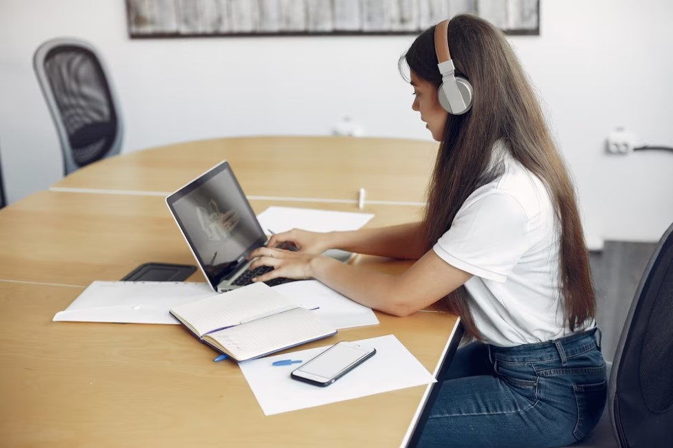 Mulher jovem trabalha no notebook com fone de ouvido