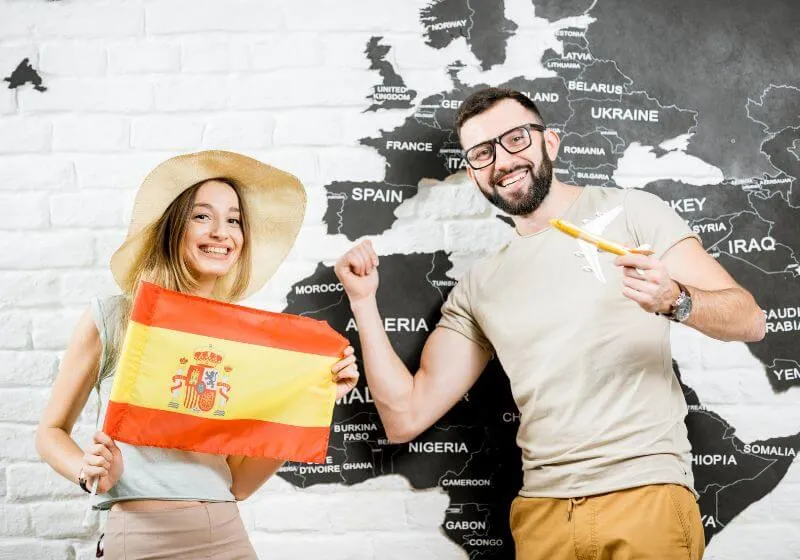 mulher segurando bandeira da Espanha e do lado um homem apontando pro mapa