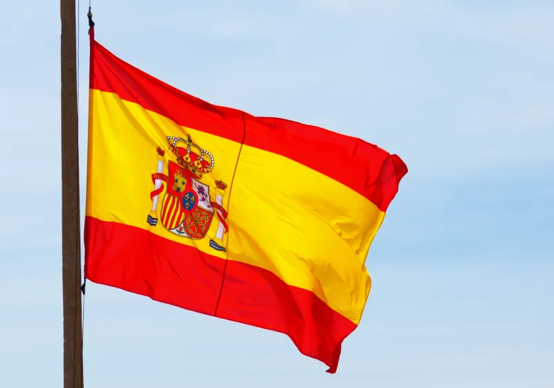 imagem de uma bandeira da Espanha em um fundo azul 