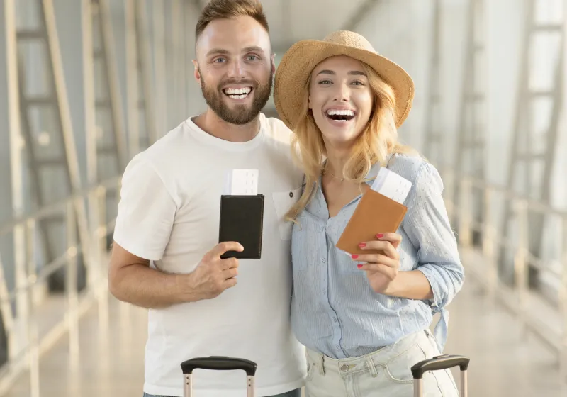 Casal feliz com passaportes e passagens no terminal do aeroporto em um fundo fosco