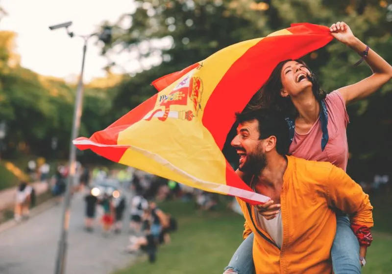 imagem Jovem casal dançando em uma pra com a bandeira da Espanha 
