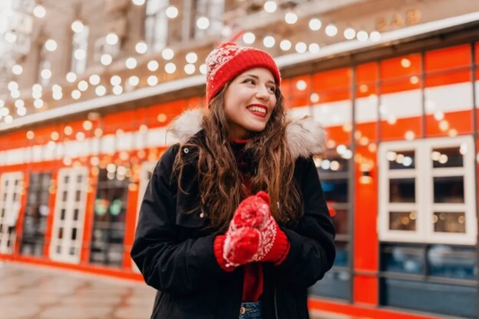 Mulher sorrindo. Está usando roupas típicas de natal