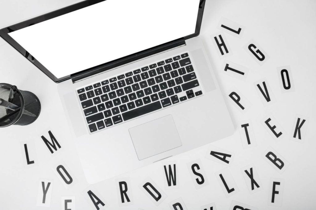 Vista elevada de laptop com várias letras do alfabeto sobre fundo branco