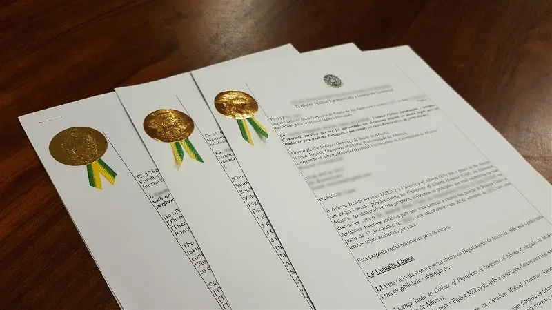 Imagem de três documentos com selo dourado sobre a mesa de um tradutor público juramentado.