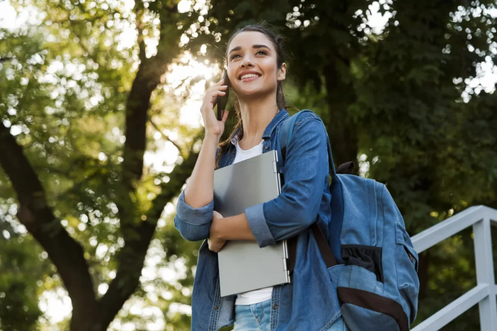 Estudante contente avisando a família pelo celular que foi aprovada no mestrado fora do Brasil