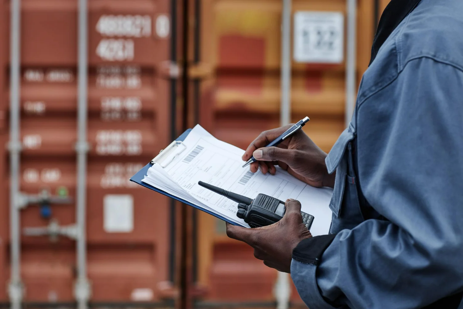 Trabalhador inspeciona carga e preenche relatórios nas docas, cenário típico que demanda tradução de documentos de importação e exportação